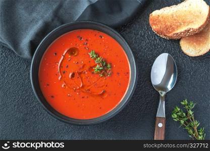 Bowl of spicy tomato soup garnished with splash of olive oil and black pepper
