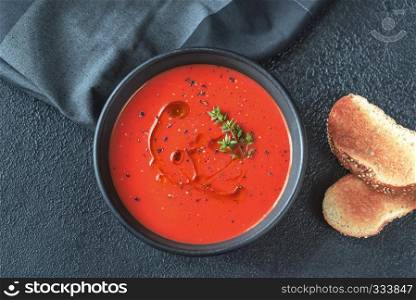 Bowl of spicy tomato soup garnished with splash of olive oil and black pepper