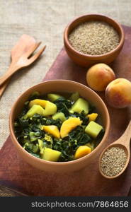 Bowl of spinach, peach and potato curry dish with sesame seeds and peaches in the back photographed with natural light (Selective Focus, Focus in the middle of the curry dish)