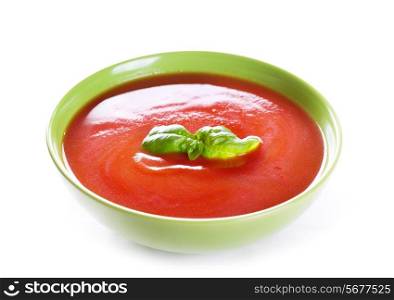 bowl of tomato soup with basil on white background