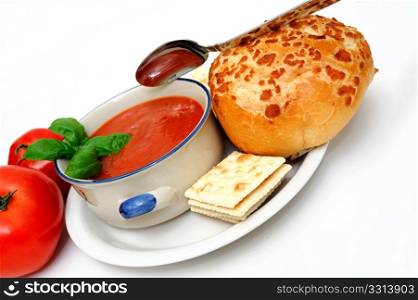 Bowl of tomato soup with crackers and a roll with fresh tomatoes isolated on a white background. Tomato Soup And Basil