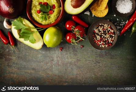 Bowl of Traditional latinamerican mexican sauce guacamole with fresh ingredients on dark rustic background. Top view