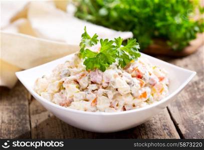 bowl of traditional russian salad on wooden table