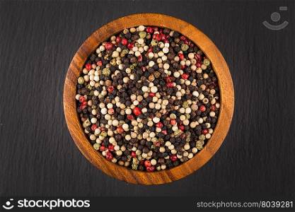 bowl of various pepper peppercorns seeds mix on black stone