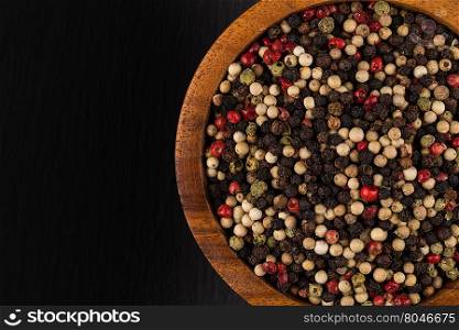 bowl of various pepper peppercorns seeds mix on black stone
