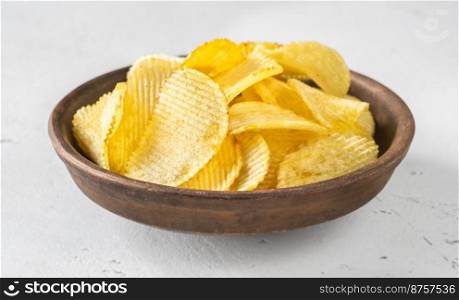 Bowl of waved potato chips on white background