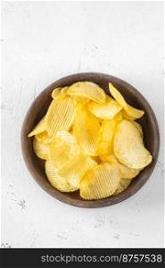 Bowl of waved potato chips on white background