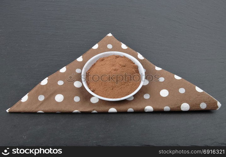 Bowl with cocoa powder on napkin and shale