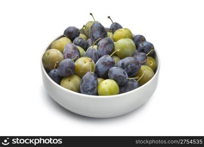 Bowl with Damson and Reine Claude plums on white background