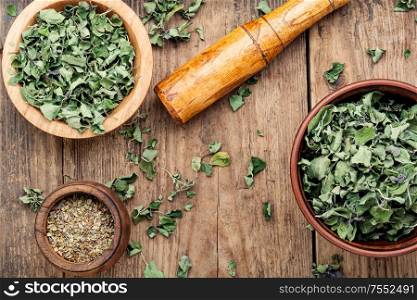 Bowl with dried oregano on old wooden table. Dried marjoram herb