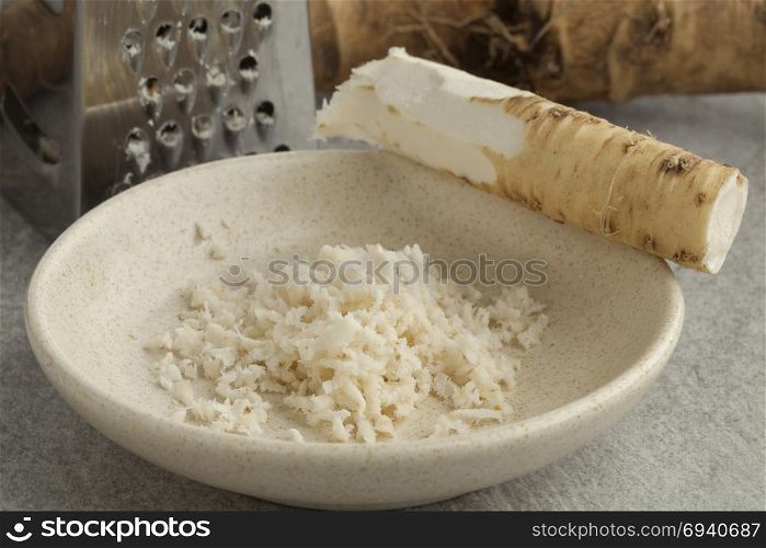 Bowl with fresh peeled and grated young horseradish close up,