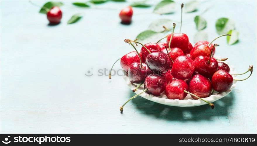 Bowl with fresh red cherry berries on light blue background, front view. Summer fruit concept