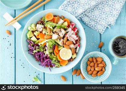 Bowl with grilled chicken meat, brown rice and fresh vegetable salad of avocado, radish, cabbage kale, carrot, and lettuce leaves. Healthy and delicious dietary lunch. Top view