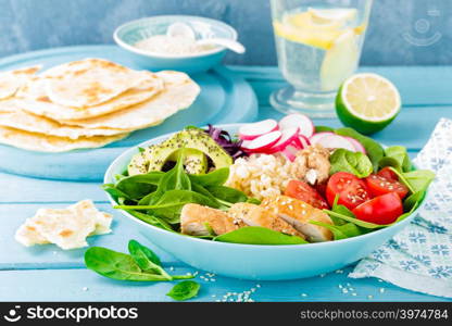 Bowl with grilled chicken meat, bulgur and fresh vegetable salad of radish, tomatoes, avocado, kale and spinach leaves. Healthy and delicious summer lunch