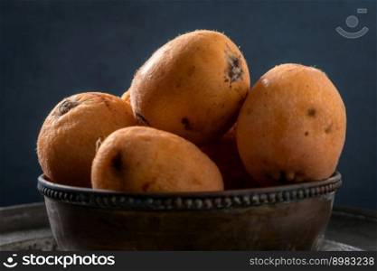 Bowl with loquats on a dark background.