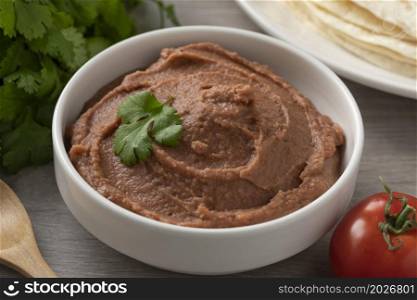 Bowl with Mexican brown refried beans paste close up