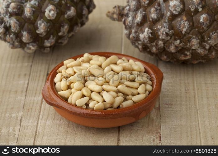 Bowl with pine nuts with pinoli, pine cones in the background
