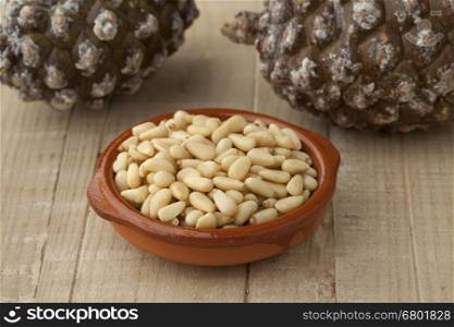Bowl with pine nuts with pinoli, pine cones in the background