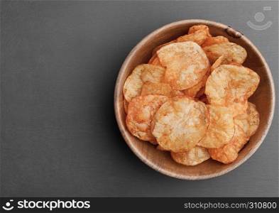 Bowl with potato crisps chips on black stone board. Junk food