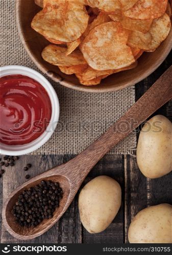 Bowl with potato crisps chips with pepper and sause on wooden board.