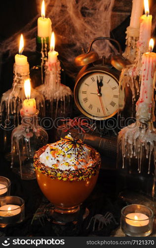 Bowl with pumpkin dessert with whipped cream on the table among the scenery for Halloween