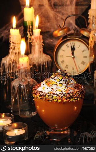 Bowl with pumpkin dessert with whipped cream on the table among the scenery for Halloween