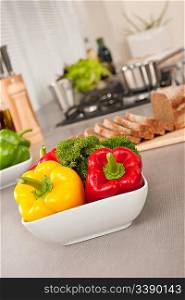 Bowl with vegetable in modern kitchen, focus on pepper