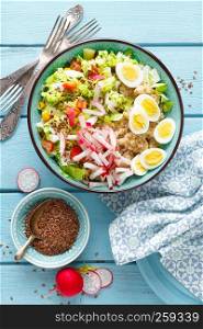 Bowl with wheat porridge, boiled quail eggs and fresh vegetable salad of radish, corn, sweet pepper and chinese cabbage. Healthy and delicious dietary lunch. Vegetarian, vegan food. Top view. Flat lay