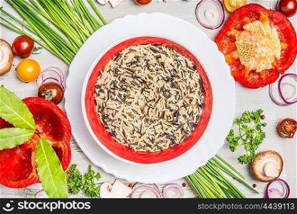 Bowl with wild rice and fresh delicious vegetables ingredients on light wooden background, top view. Vegan , vegetarian,or diet food concept