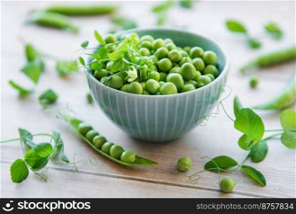 Bowl with young fresh juicy pods of green peas on a wooden background. Healthy organic food. 