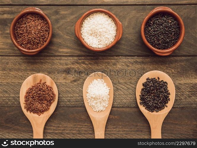 bowl wooden spoon with white red black rice grains wooden table