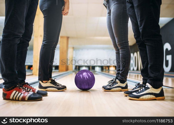 Bowling alley team, feet of the players in house shoes and ball on lane. Friends playing the game in club, active leisure