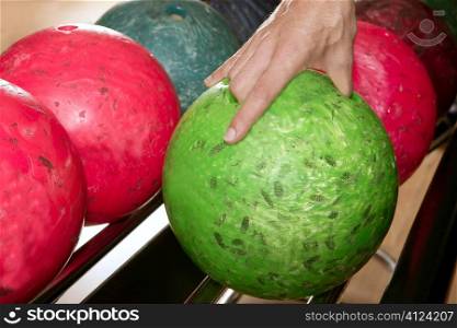 Bowling ball in player man hand in colorful rows