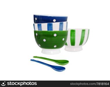 Bowls in blue and green and different patterns and two spoons on white background