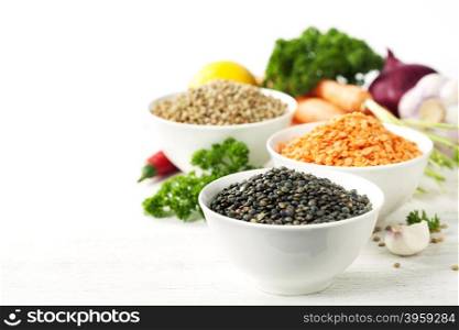 Bowls of assorted dried lentils with vegetables over white