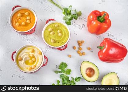 Bowls of different kinds of hummus  classic, avocado and paprika