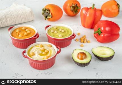 Bowls of different kinds of hummus  classic, avocado and paprika-persimmon