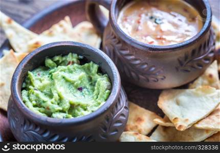 Bowls of guacamole and queso with tortilla chips