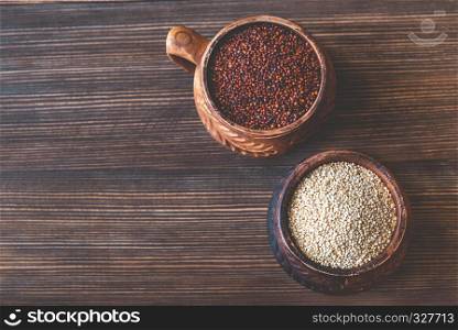 Bowls of raw white and red quinoa on the wooden background