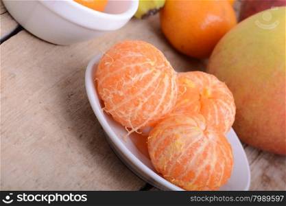 Bowls of slices mandarin with apple on rustic wooden background