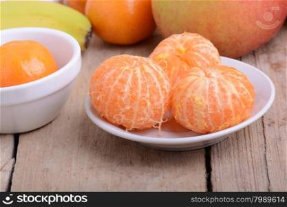 Bowls of slices mandarin with apple on rustic wooden background