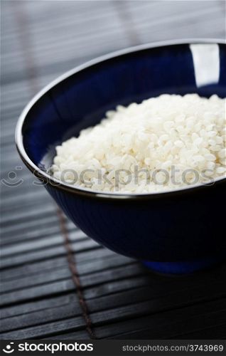 bowls of uncooked rice on bamboo background
