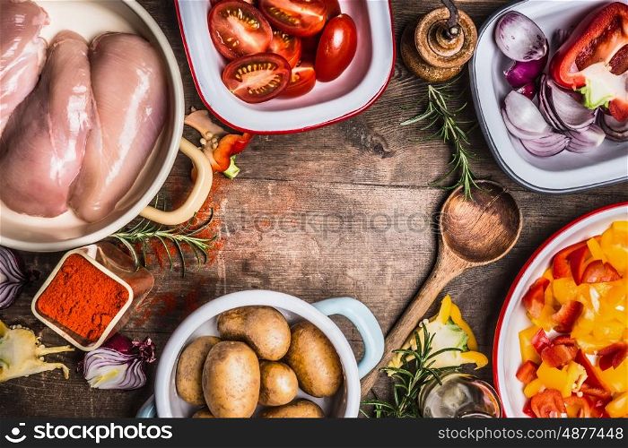 Bowls with chicken , various vegetables and cooking spoon and spices on rustic wooden background, top view, frame