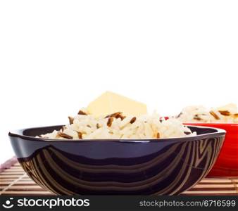 bowls with cooked rice and butter on bamboo napkin