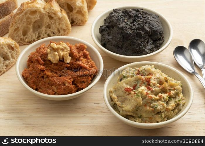 Bowls with fresh home made Baba ganoush, Muhammara and black Hummus close up for appetizer
