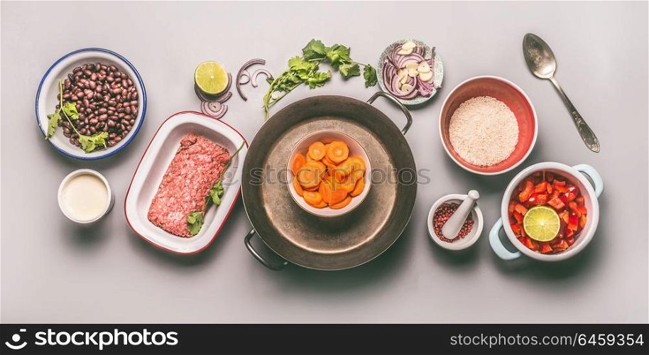 Bowls with ingredients for balanced one pan meal with beans, minced meat, rice and vegetables on gray background, top view, flat lay