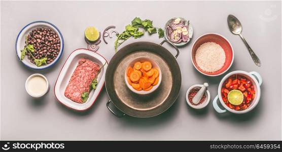 Bowls with ingredients for balanced one pan meal with beans, minced meat, rice and vegetables on gray background, top view, flat lay