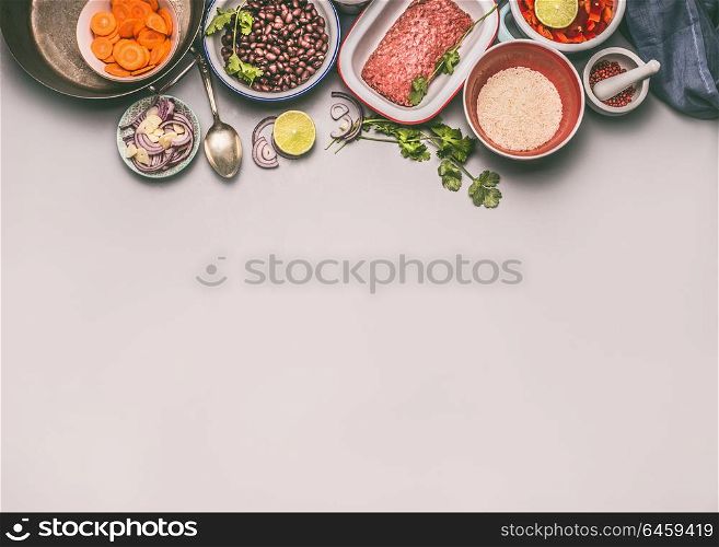 Bowls with ingredients for balanced one pan meal with beans, minced meat, rice and cut vegetables on gray background, top view, border or food background