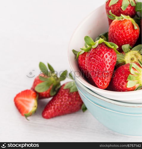 Bowls with strawberries on white table background.