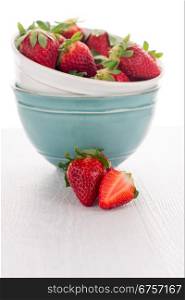 Bowls with strawberries on white table background.